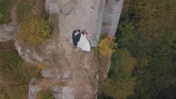 Novomanželé stojí na vysokém svahu hory. Ženich a nevěsta. Letecký pohled — Stock video