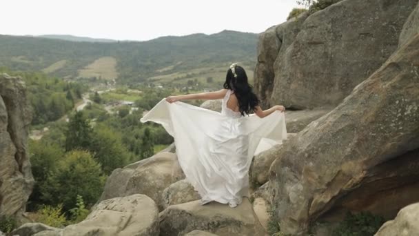 Hermosa y encantadora novia de pie en las colinas de montaña. Mujer enamorada — Vídeos de Stock