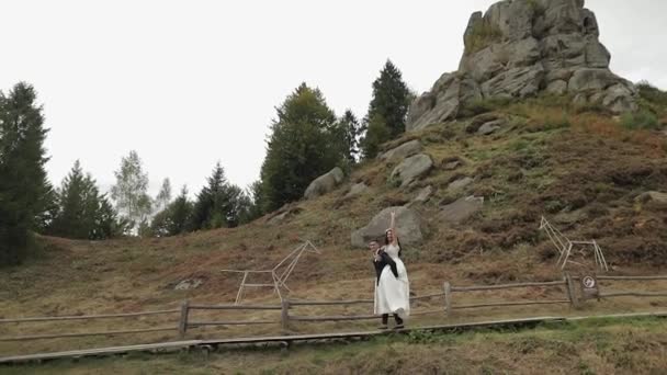 A vőlegény menyasszonnyal a hegyekben sétál. Szerelmes házaspár. — Stock videók