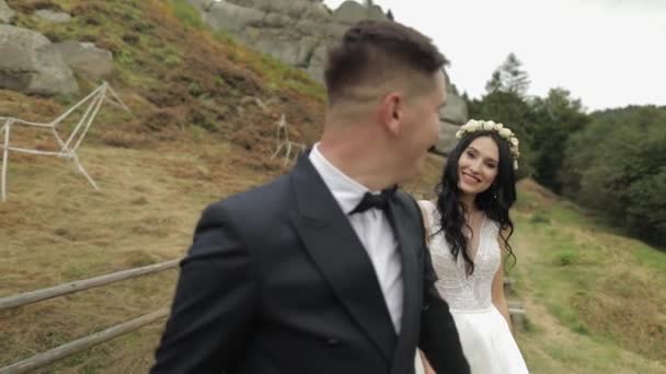 Novio con novia caminando cerca de las colinas de montaña. Pareja de bodas. Recién casados — Vídeos de Stock