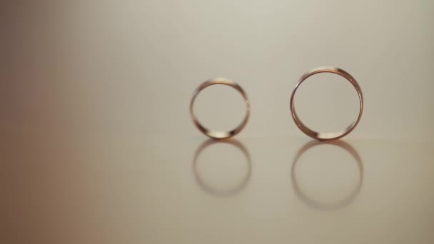 Anillos de oro de boda rodar el uno al otro. Primer plano, macroplano — Vídeos de Stock