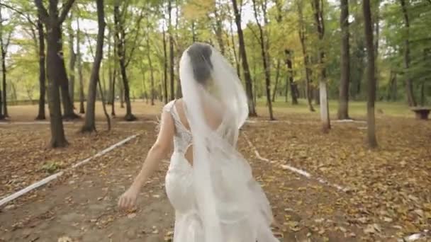Όμορφη και υπέροχη νύφη στο νυφικό τρέχει στο πάρκο. Αργή κίνηση — Αρχείο Βίντεο