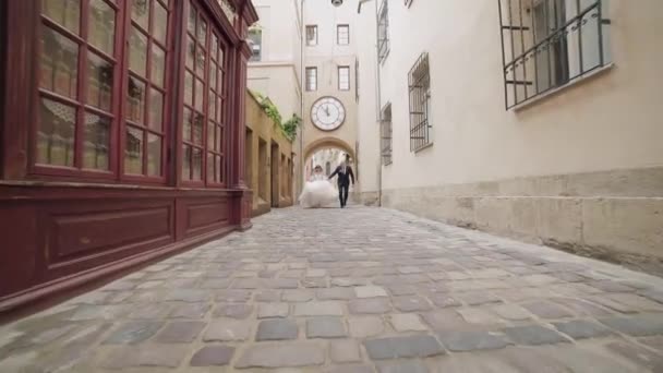 Recién casados corriendo en el centro del casco antiguo. Novia y novio. Boda — Vídeo de stock