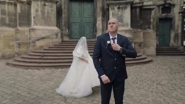 Nygifta i centrum av staden. Brud och brudgum nära gamla kyrkan — Stockvideo