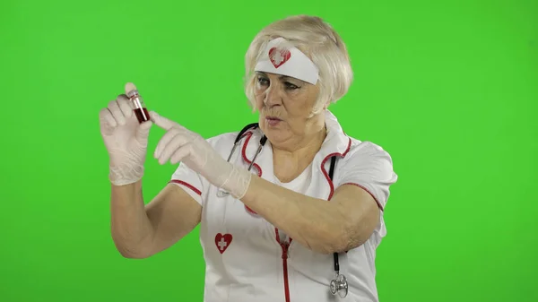 Elderly caucasian female doctor with test tube with analyzes. Coronavirus — 图库照片