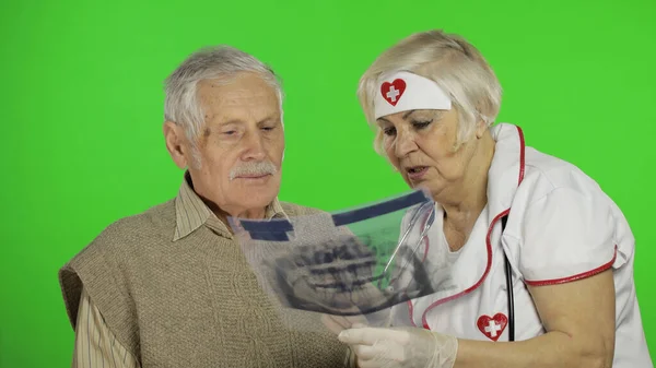 Mature woman nurse doctor examines senior patient man with problems — Stockfoto