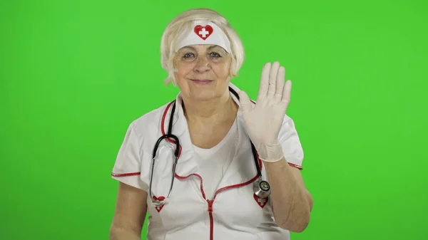 Anciana caucásica doctora en máscara protectora. Agitando sus manos — Foto de Stock