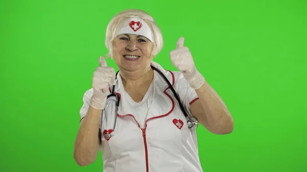Anciana médica caucásica. Enfermera. Muestra señal OK. Pulgares arriba — Foto de Stock