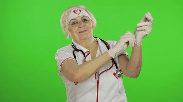 Elderly caucasian female doctor wearing protective gloves. Pandemic. Coronavirus — Stockfoto