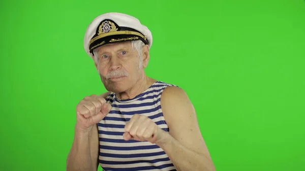 Homem idoso marinheiro está com raiva e mostra punhos. Sailorman no fundo da chave chroma — Fotografia de Stock