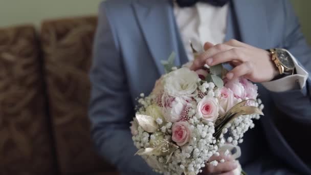 Groom with wedding bouquet in his hands at home. White shirt, jacket — Stock Video