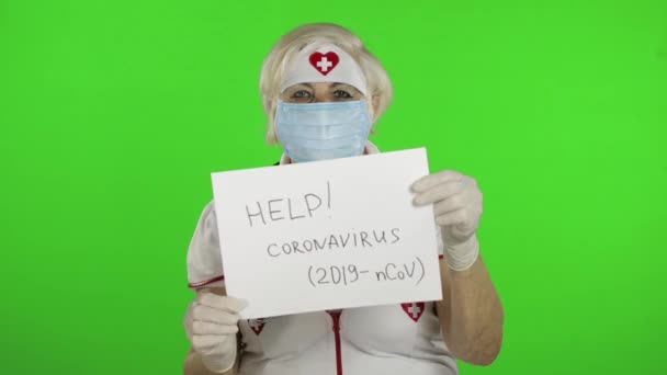 Пожилая женщина-врач в медицинской маске показывает страницу с сообщением. Коронавирус — стоковое видео