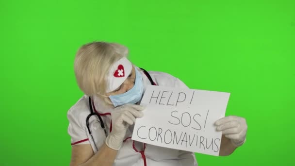 Пожилая женщина-врач в медицинской маске показывает страницу с сообщением. Коронавирус — стоковое видео
