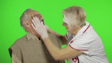 Mature woman nurse doctor examines senior patient man with problems
