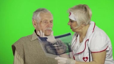 Mature woman nurse doctor examines senior patient man with problems