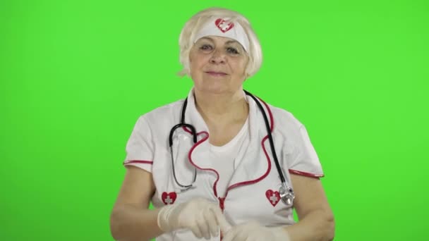 Elderly caucasian female doctor wearing protective gloves. Pandemic. Coronavirus — Stockvideo