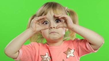 Olumlu kız duygusal olarak yüzler yapar ve pembe bluz içinde gülümser. Krom Anahtar