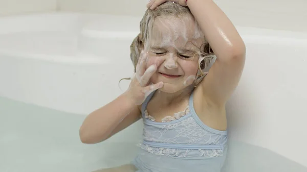 Schattig blond meisje neemt een bad in badmode. Klein kind wast haar hoofd — Stockfoto