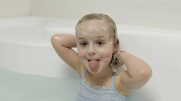 Aranyos szőke lány fürdőruhában fürdik. A gyerek megmossa a fejét. — Stock Fotó