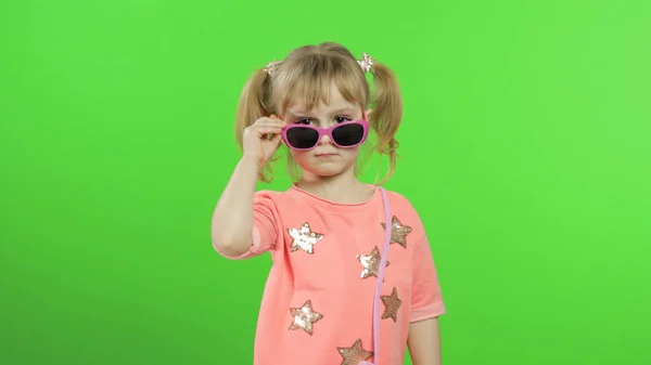 Positiv tjej i rosa blus och solglasögon poserar och gör ansikten. Kromnyckel — Stockfoto