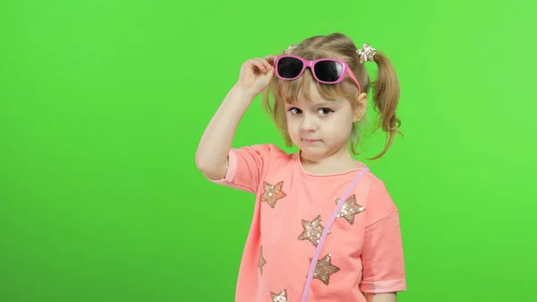 Θετικό κορίτσι με ροζ μπλούζα και γυαλιά ηλίου που ποζάρει και κάνει γκριμάτσες. Κλειδί χρωμίου — Φωτογραφία Αρχείου