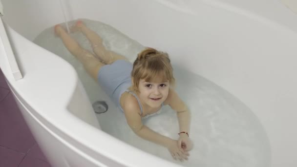 Cute blonde girl takes a bath in swimwear. Little child, 4 years old. Hygiene — Stock Video