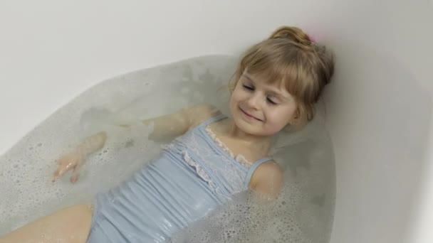 Nettes blondes Mädchen nimmt ein Bad in Badebekleidung. Kleines Kind, 4 Jahre alt. Hygiene — Stockvideo