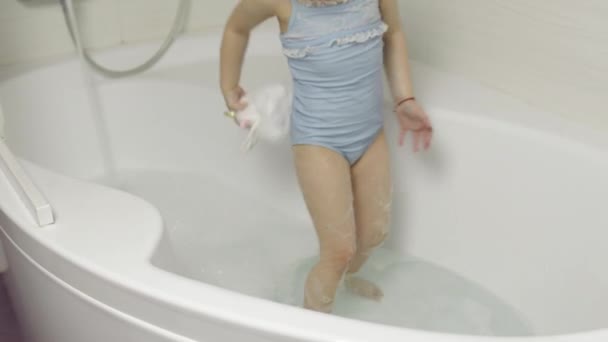 Jolie fille blonde prend un bain en maillot de bain. Petit enfant de 4 ans. Hygiène — Video