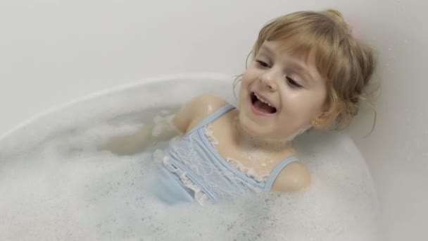 Linda chica rubia toma un baño en traje de baño. Niña, 4 años. Higiene — Vídeo de stock