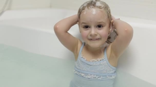 Tatlı sarışın kız mayo banyosu yapıyor. Küçük çocuk başını yıkıyor. — Stok video