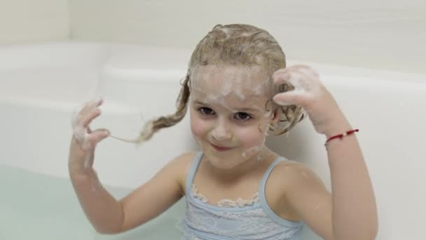 Słodka blondynka bierze kąpiel w strojach kąpielowych. Małe dziecko myje głowę. — Wideo stockowe