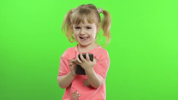 Egy kislány okostelefont használ. Portré gyermek okostelefon szöveges, játék — Stock videók
