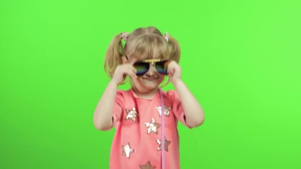 Позитивная девушка в розовой блузке и солнечных очках танцует и позирует. Ключ хромы — стоковое видео