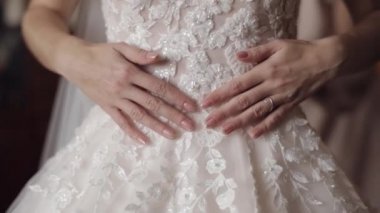 Güzel ve güzel gelin, gelinliğine elleriyle dokunuyor. Yavaş çekim