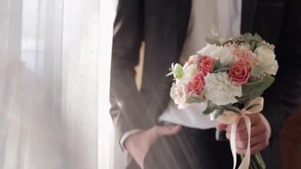 Ženich se svatební kyticí v rukou doma. Bílá košile, bunda — Stock video