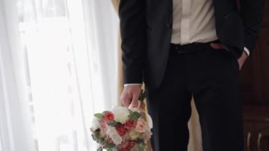 Evde elinde düğün buketi olan damat. Beyaz gömlek, ceket.