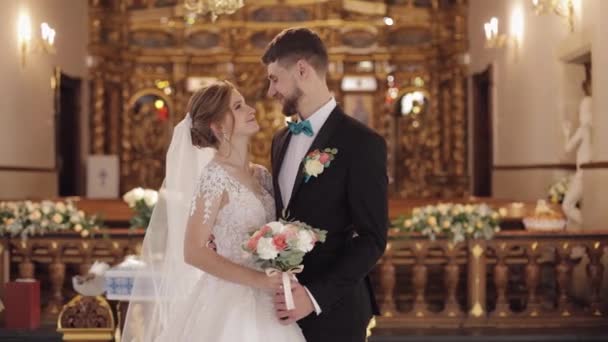 Yeni evliler. Beyaz gelin ve damat eski bir kilisede bir arada. Düğün. — Stok video