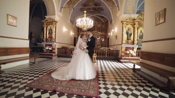 Νιόπαντροι. Λευκή νύφη και γαμπρός μαζί σε μια παλιά εκκλησία. Γάμος — Αρχείο Βίντεο
