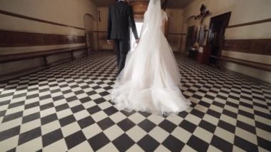 Yeni evliler. Beyaz gelin ve damat eski bir kilisede birlikte yürüyorlar. Düğün.