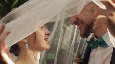 Yeni evliler. Gelin ve beyaz damat peçenin altında öpüşüyor. Düğün çifti