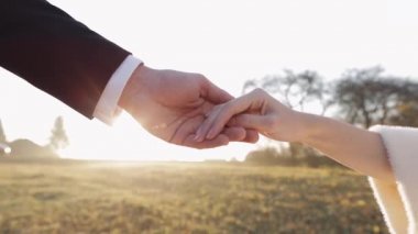 Yeni evliler. Sabah güneşlerinde gelinle damat elleri. Düğün çifti