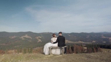 Yeni evliler. Dağın yamacında gelinle birlikte beyaz bir damat. Düğün çifti. Mutlu