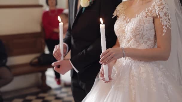 Les jeunes mariés. Mariée et le marié se tiennent à l'église, tenant des bougies dans leurs mains — Video