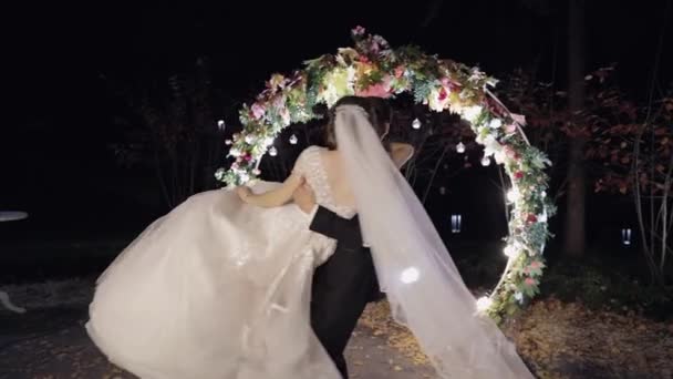 Nygifta. Vit brudgum med brud nära tunnland av blommor. Nattetid — Stockvideo