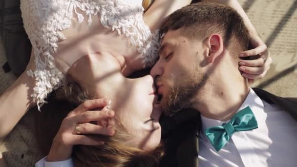 Pasgetrouwden. Kaukasische bruidegom met bruid liggen naast elkaar op de grond — Stockvideo