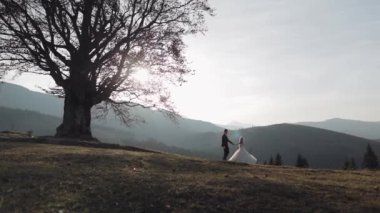 Yeni evliler. Dağın yamacında gelinle birlikte beyaz bir damat. Düğün çifti. Mutlu