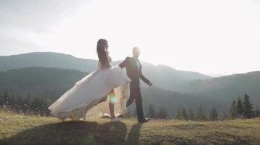 Yeni evliler. Dağın yamacında koşan beyaz bir damat ve gelin. Düğün çifti