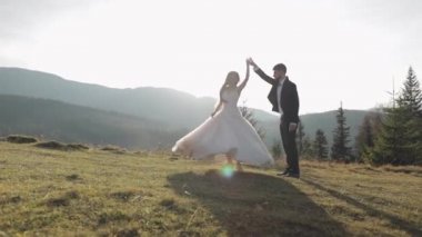 Yeni evliler. Dağın yamacında dans eden beyaz bir damat ve gelin. Düğün çifti