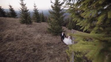 Yeni evliler. Dağın yamacında yürüyen beyaz bir damat ve gelin. Düğün çifti