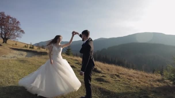 Friss házasok. Kaukázusi vőlegény menyasszonnyal, aki a hegyoldalon táncol. Esküvői pár — Stock videók